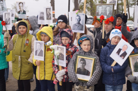Дети участвуют в памятном шествии и держат портреты қатысушылар Великой Отечественной войны.